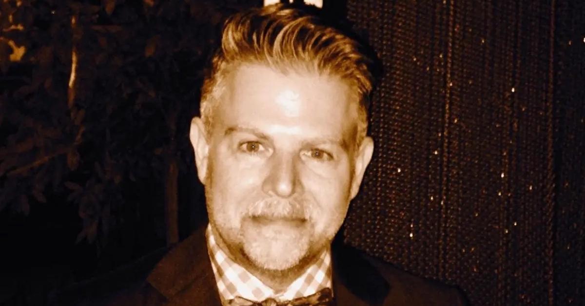 Adam Rich wearing a checkered shirt and jacket.